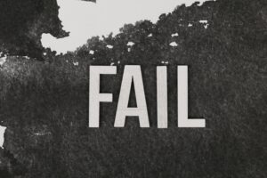 Grayscale image of the word 'FAIL' on a textured, monochrome background.